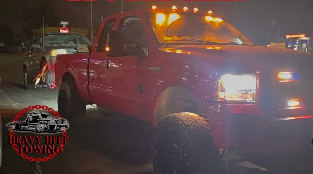 Heavy Hitt Towing red tow truck on a San Diego street at night